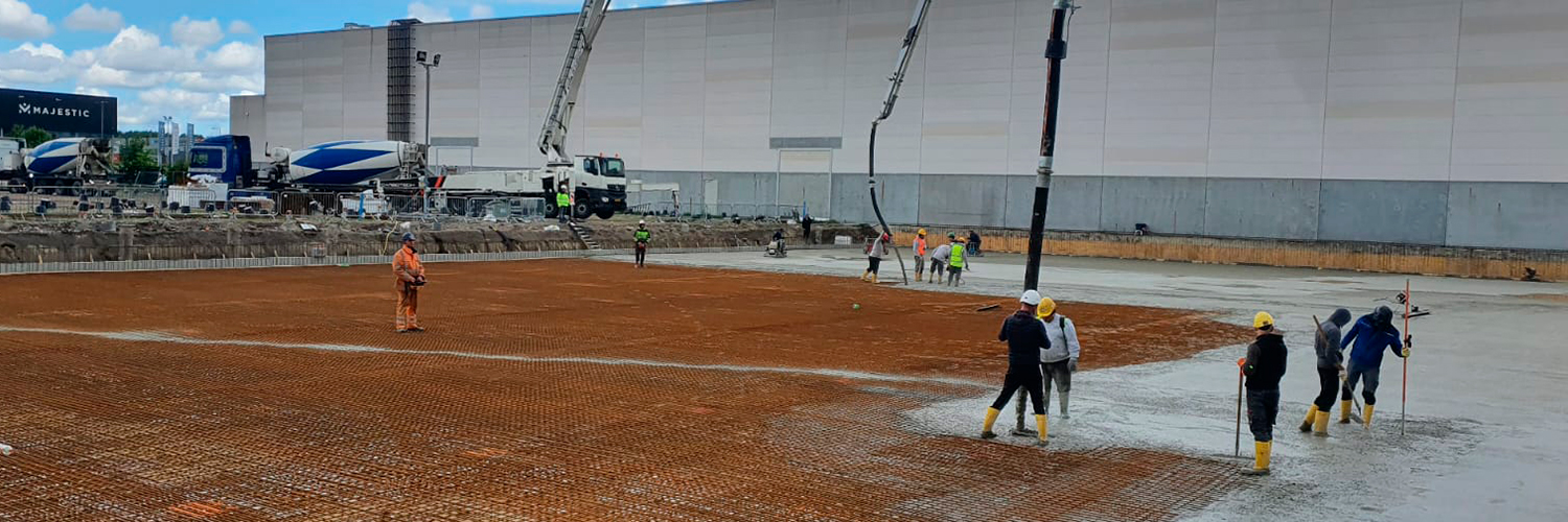 Pouring cement or concrete with a concrete mixer truck, construction site with a reinforced grillage foundation. Workers settle and level the concrete in the foundation